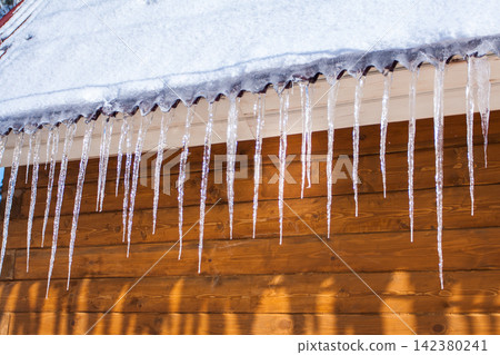 Icicles dropping from roof of wooden house Icicles dropping from roof of wooden house 142380241