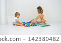 Sisters sitting on the floor sorting through a large pile of colorful plastic construction blocks. Educational bonding concept 142380482