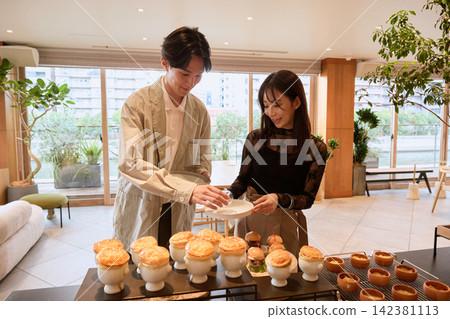 A couple enjoying a meal, serving themselves pot pies from a buffet. A couple enjoying a meal, serving themselves pot pies from a buffet. 142381113