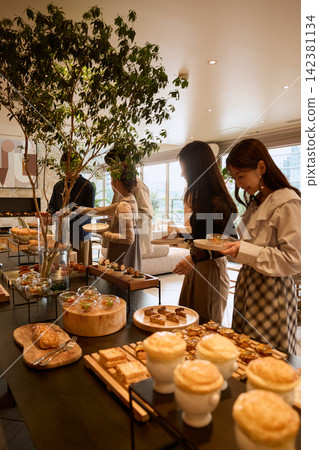 Women enjoying an afternoon tea buffet at a hotel. Women enjoying an afternoon tea buffet at a hotel. 142381134