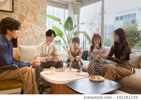 五位年輕男女在時尚咖啡館享用甜點。 142381139