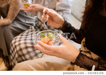 派對上，一位女士正在享用盛在玻璃盤中的開胃菜。 142381158