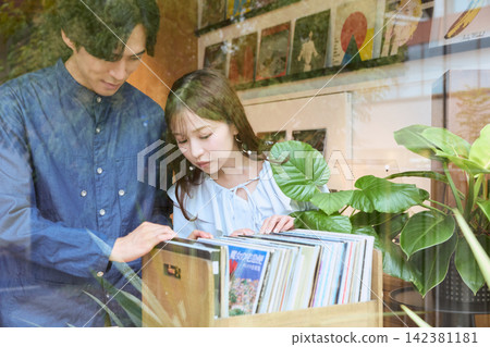 一對年輕夫婦在唱片行挑選唱片 一對年輕夫婦在唱片行挑選唱片 142381181