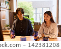 一對年輕情侶在咖啡館愉快地交談，手裡拿著酒杯。 142381208