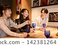三位年輕男女手持藍色酒杯，在酒吧愉快地交談。 142381264