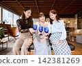 三位年輕女子在時尚的休息室裡舉著藍色玻璃杯碰杯。 142381269