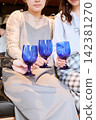 三位女士舉起藍色玻璃杯碰杯。 142381270