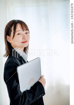 A young woman in a suit holding a laptop A young woman in a suit holding a laptop 142381879