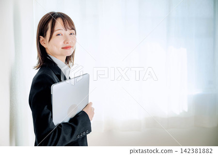 A young woman in a suit holding a laptop A young woman in a suit holding a laptop 142381882