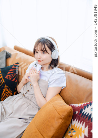 A woman in her 20s listening to music with headphones. A woman in her 20s listening to music with headphones. 142381949