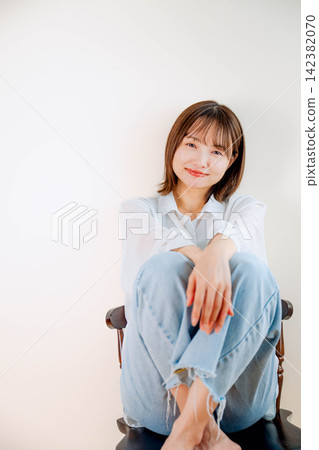 A young woman sitting in a chair with her legs stretched out. A young woman sitting in a chair with her legs stretched out. 142382070