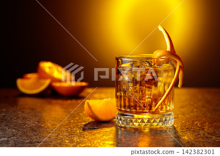 Old-fashioned cocktail in a fogged up glass on a black stone table. Old-fashioned cocktail in a fogged up glass on a black stone table. 142382301
