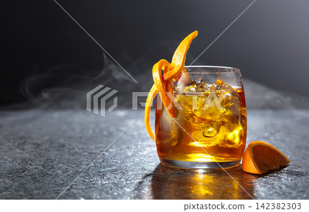 Whiskey with ice in a fogged up glass on a black stone table. Whiskey with ice in a fogged up glass on a black stone table. 142382303