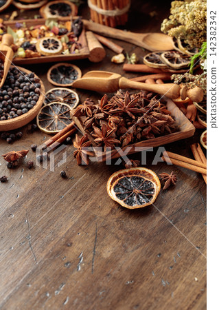 Rustic arrangement of juniper berries, dried citrus, cinnamon and aromatic herbs on a wooden table. Rustic arrangement of juniper berries, dried citrus, cinnamon and aromatic herbs on a wooden table. 142382342