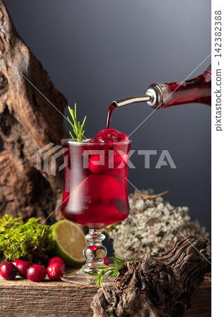 Cranberry cocktail with ice, lime, and rosemary on a old wooden board. Cranberry cocktail with ice, lime, and rosemary on a old wooden board. 142382388