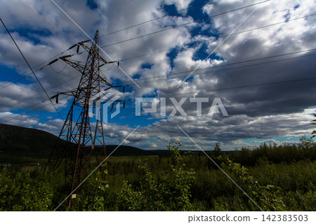 High voltage electricity transmission tower and power lines crossing a remote mountain landscape in the Khibiny Mountains, Murmansk Region, Russia. Energy infrastructure surrounded by northern vegetat High voltage electricity transmission tower and power lines crossing a remote mountain landscape in the Khibiny Mountains, Murmansk Region, Russia. Energy infrastructure surrounded by northern vegetat 142383503