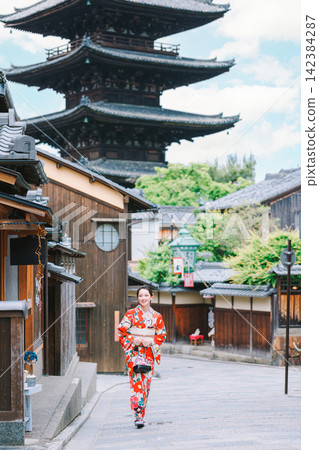 A young woman in a kimono stands with the Yasaka Pagoda in the background. A young woman in a kimono stands with the Yasaka Pagoda in the background. 142384287