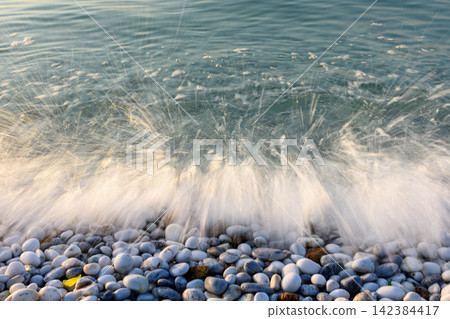 A dynamic coastal scene with a breaking wave on pebble beach A dynamic coastal scene with a breaking wave on pebble beach 142384417