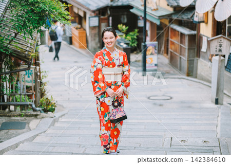 A woman in a kimono walking through the streets of Kyoto (Ninenzaka). A woman in a kimono walking through the streets of Kyoto (Ninenzaka). 142384610