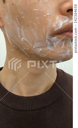 一名男子在臉上塗抹麻醉膏,準備去除鬍鬚。 一名男子在臉上塗抹麻醉膏,準備去除鬍鬚。 142384656