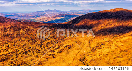 The photograph captures a vast expanse of mountains, illuminated by sunlight that creates stark contrasts between light and shadow. The photograph captures a vast expanse of mountains, illuminated by sunlight that creates stark contrasts between light and shadow. 142385396
