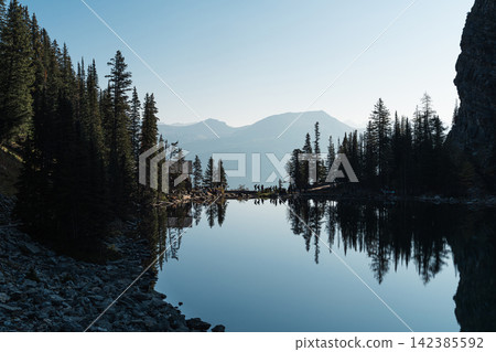 加拿大艾格尼絲湖茶館前的艾格尼絲湖和針葉林倒映在平靜的湖上。 加拿大艾格尼絲湖茶館前的艾格尼絲湖和針葉林倒映在平靜的湖上。 142385592