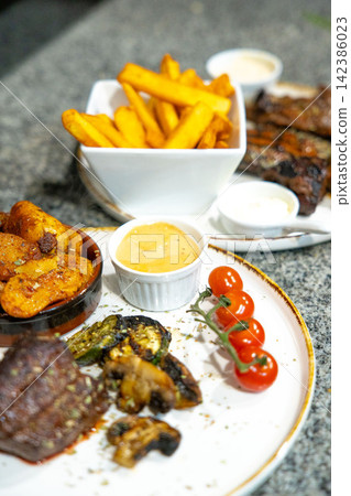 Perfectly Grilled Steak with Sides of Crispy French Fries. Grilled Steak with Tomatoes and Fresh Herbs Perfectly Grilled Steak with Sides of Crispy French Fries. Grilled Steak with Tomatoes and Fresh Herbs 142386023
