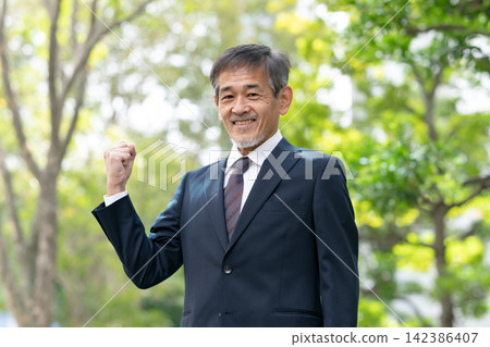 一位身著西裝的老者,周圍環繞著新鮮的綠植,擺出勝利的姿勢。 一位身著西裝的老者,周圍環繞著新鮮的綠植,擺出勝利的姿勢。 142386407
