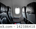 Airplane cabin interior, empty comfortable passenger seats in economy class with portholes. 142386418