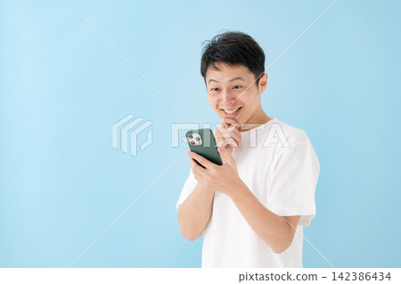 A man looking at a smartphone with a smile A man looking at a smartphone with a smile 142386434