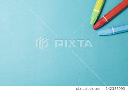 Three colorful drawing crayons placed in the corner of a clean bright blue background, providing ample copy space for creative projects. High Quality Photo Three colorful drawing crayons placed in the corner of a clean bright blue background, providing ample copy space for creative projects. High Quality Photo 142387093