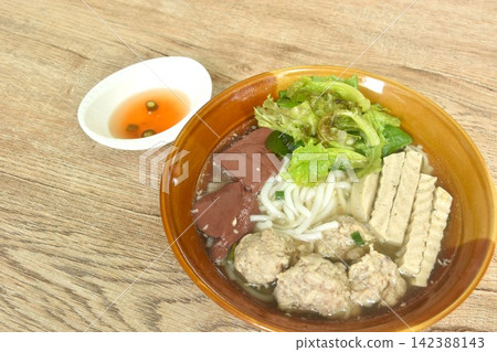 Vietnamese rice noodles or Pho with slice sausage and chop pork couple blood topping vegetable in soup on bowl dipping spicy sour chili sauce Vietnamese rice noodles or Pho with slice sausage and chop pork couple blood topping vegetable in soup on bowl dipping spicy sour chili sauce 142388143