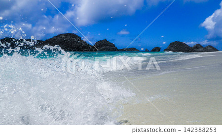 [Chichijima Island] The waves and blue sea at the secluded Ginny Beach, with raindrops and sunlight sparkling at the water's edge (16:9) 142388253