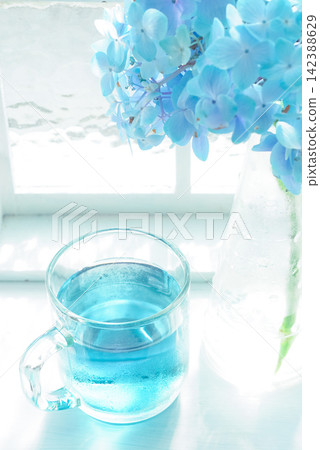 在藍色的夏日飲品中加入藍色鮮花。 在藍色的夏日飲品中加入藍色鮮花。 142388629