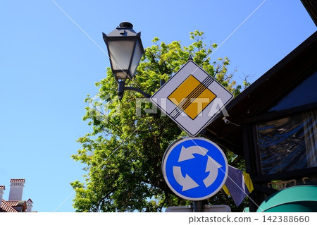 Road Signs Showing End of Priority Road and Mandatory Roundabout Near Traditional Street Lantern in Kamianets Podilskyi Ukraine Road Signs Showing End of Priority Road and Mandatory Roundabout Near Traditional Street Lantern in Kamianets Podilskyi Ukraine 142388660