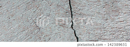 A vertical crack on a textured, light-gray concrete surface. A vertical crack on a textured, light-gray concrete surface. 142389631