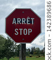 A red road sign that says "STOP" in English and French. 142389686