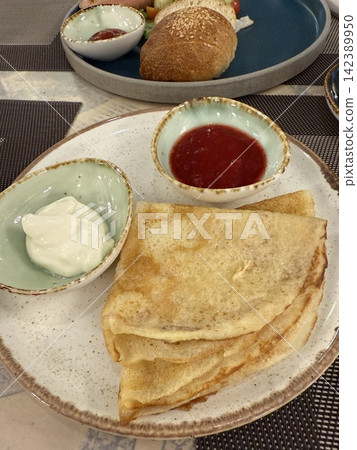 Pancakes served with jam and cream on rustic plate, top view food background 142389950