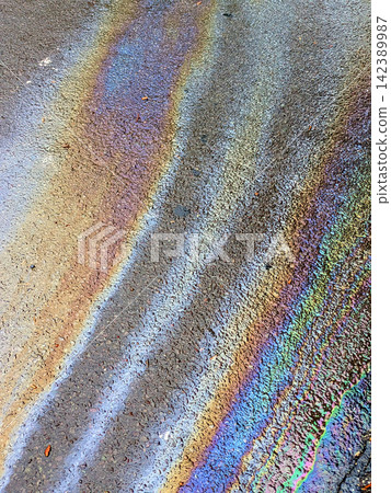A leaked Car Oil Petrol in The Rain on a Tarmac Road Metallic Rainbow Gasoline A leaked Car Oil Petrol in The Rain on a Tarmac Road Metallic Rainbow Gasoline 142389987