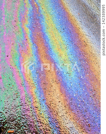 A leaked Car Oil Petrol in The Rain on a Tarmac Road Metallic Rainbow Gasoline A leaked Car Oil Petrol in The Rain on a Tarmac Road Metallic Rainbow Gasoline 142389995