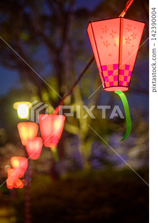 A beautifully composed photograph of illuminated lanterns in a garden or park setting with a warm A beautifully composed photograph of illuminated lanterns in a garden or park setting with a warm 142390004