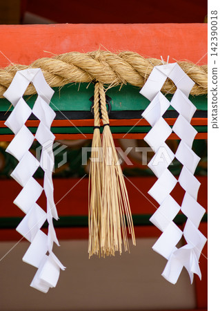A close-up photograph showcasing traditional Japanese ceremonial decorations on a wooden beam. A close-up photograph showcasing traditional Japanese ceremonial decorations on a wooden beam. 142390018