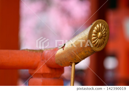 A detailed golden cylindrical item set against a softly blurred background, likely part of a traditional Japanese shrine or ceremonial practice A detailed golden cylindrical item set against a softly blurred background, likely part of a traditional Japanese shrine or ceremonial practice 142390019