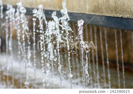 A close-up photograph of a modern water fountain showing dynamic movement of cascading water with visible splashes A close-up photograph of a modern water fountain showing dynamic movement of cascading water with visible splashes 142390025