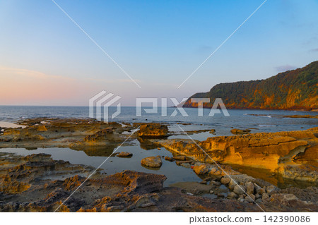 The rocky shore and tide pools illuminated by the warm evening light. The rocky shore and tide pools illuminated by the warm evening light. 142390086