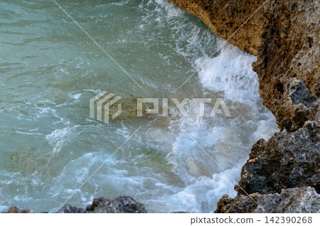 A dynamic coastal view from above, showing powerful waves crashing against rugged rock formations A dynamic coastal view from above, showing powerful waves crashing against rugged rock formations 142390268