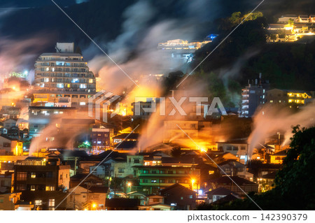 Beppu town with heavy steam of hot spring bath ryokan at night, Oita 142390379