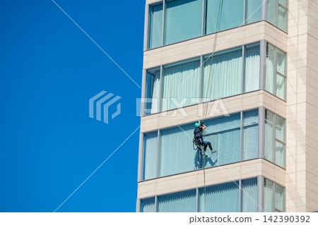 Window cleaner works on high rise building against blue sky, Fukuoka Window cleaner works on high rise building against blue sky, Fukuoka 142390392