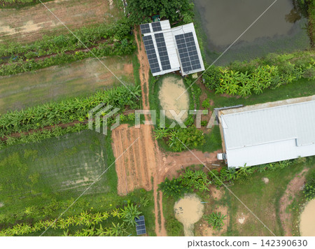 Aerial top view of integrated tropical farm with rooftop solar panels, combining renewable energy, sustainable agriculture and food production. Clean energy, food security and rural development. 142390630
