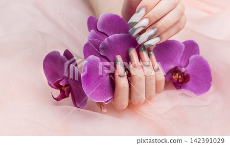 Female hands displaying long creative nail art with orchids Female hands displaying long creative nail art with orchids 142391029